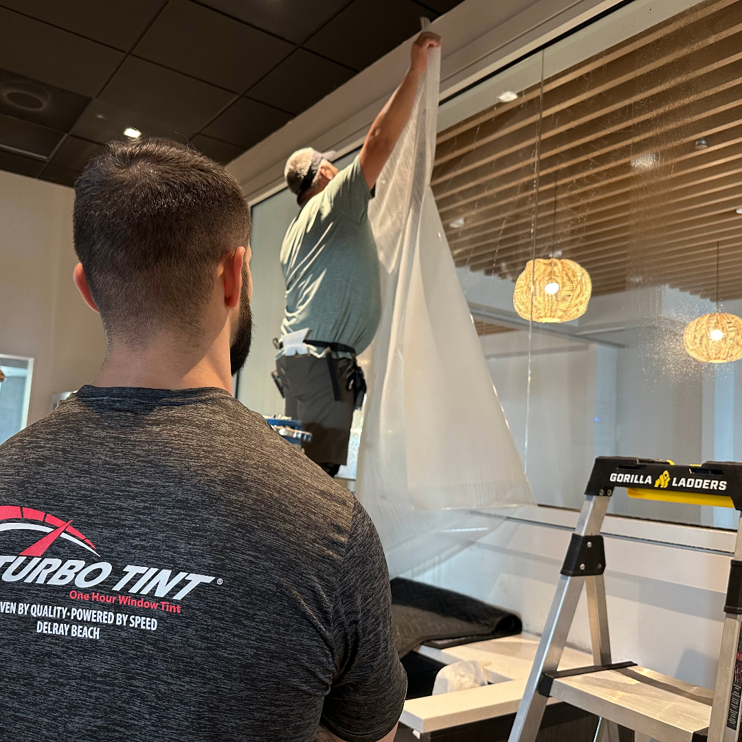 Technician preparing commercial window tinting film using a white sheet.