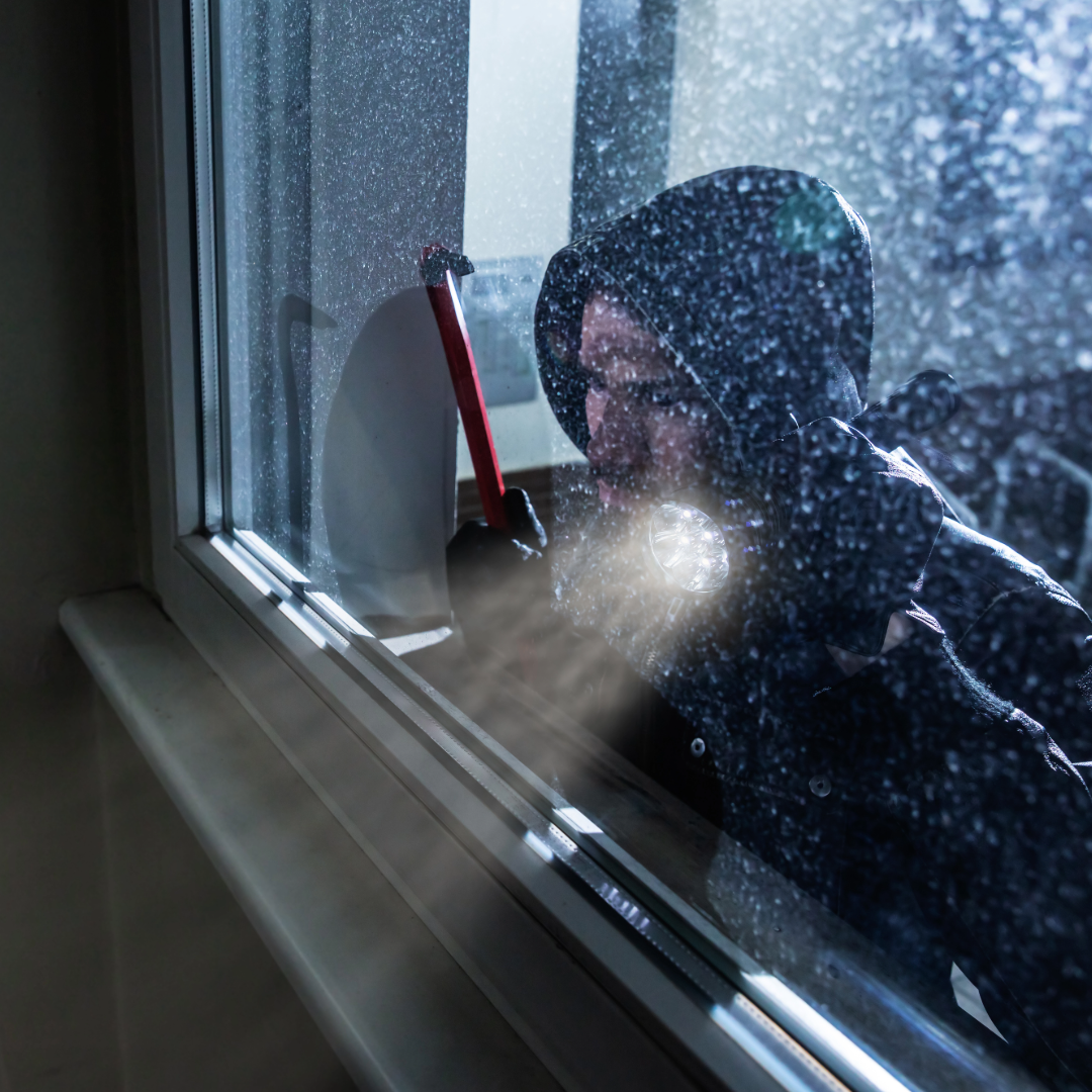 A man with a flashlight and an axe looking out a residential window protected by security-grade window tint film.
